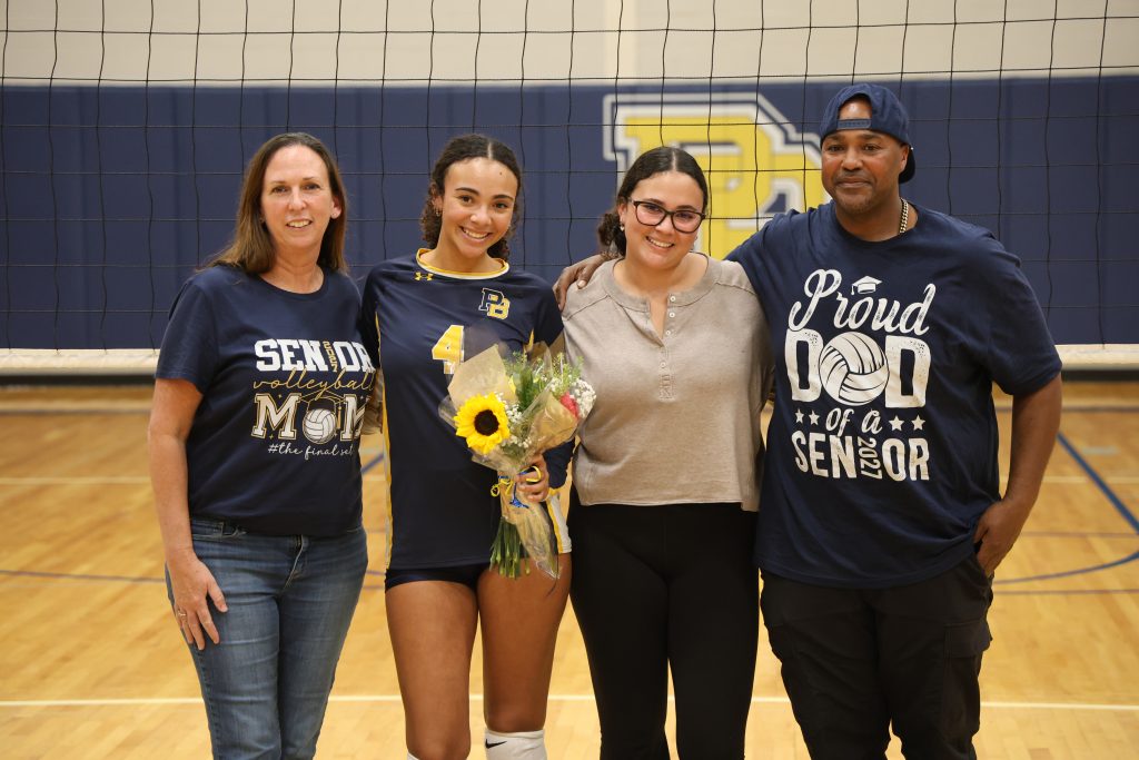 volleyball player with her parents standing for picture