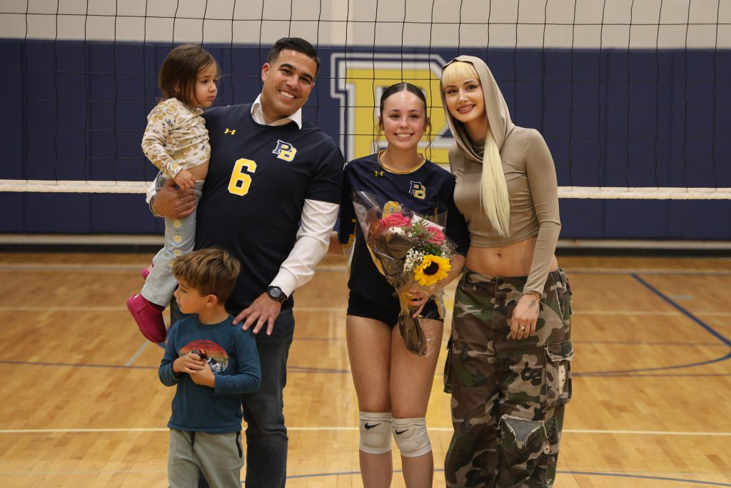 volleyball player with her parents standing for picture