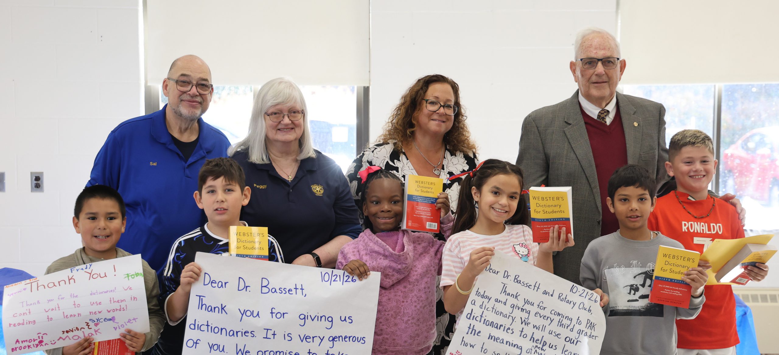 group of kids standing in front of adults holding a poster