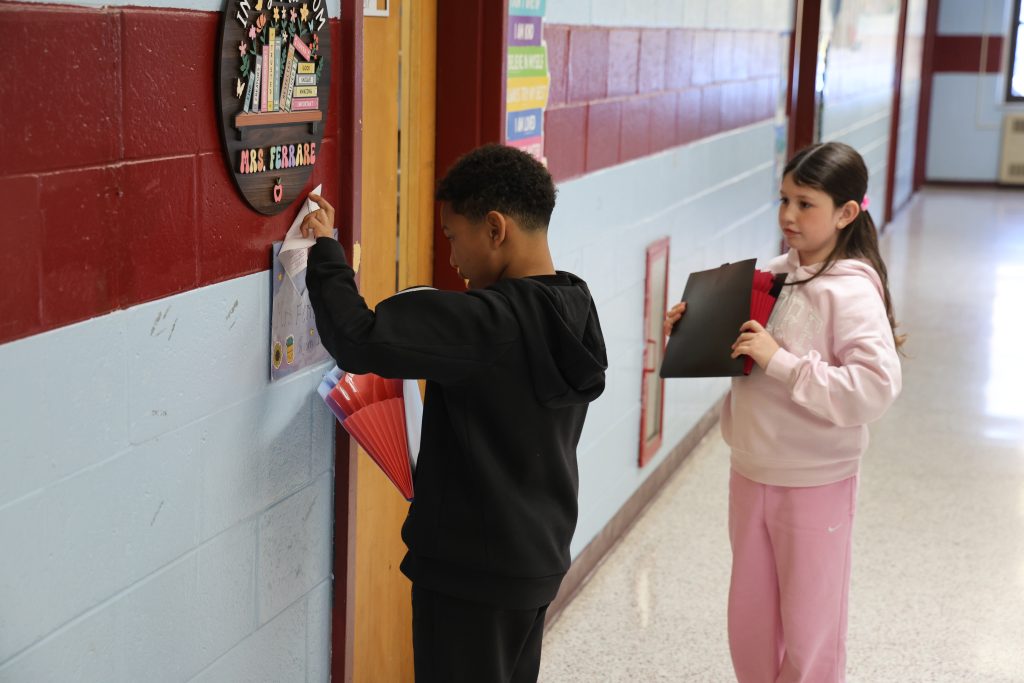 kids putting mail in a hand-made classroom mailbag