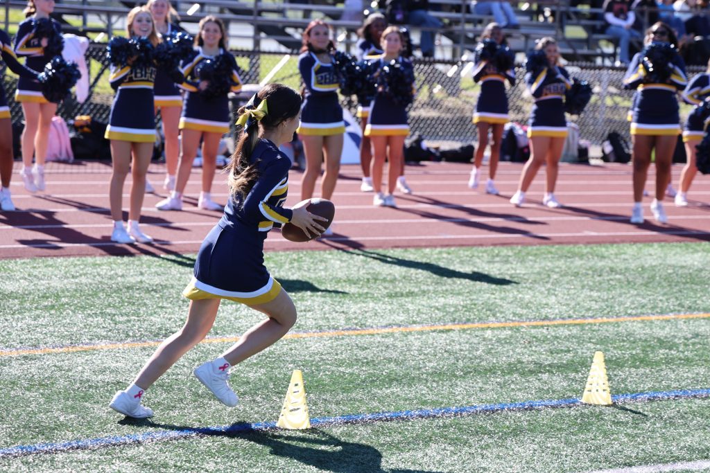 cheerleader running with football at an obstacle course