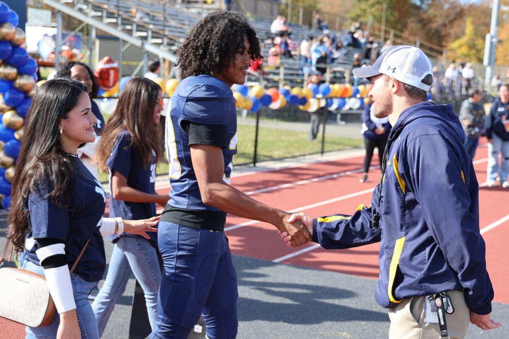 football player shaking his coach's hand