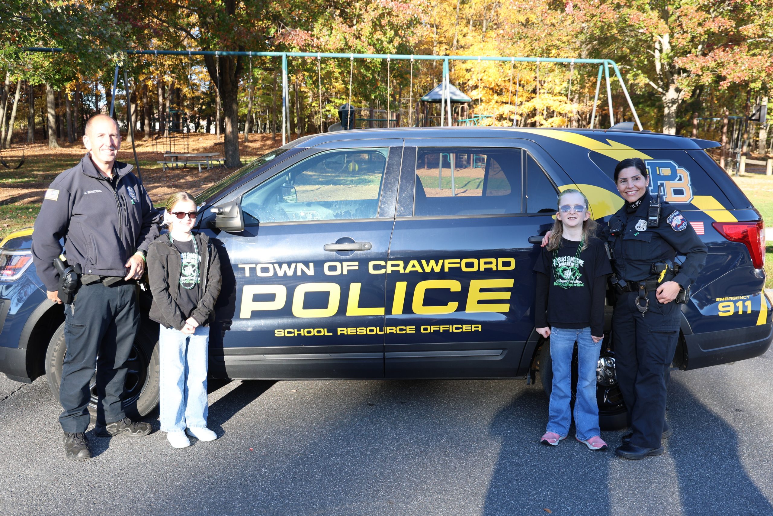 police officers taking photo of elementary students in front of a police car