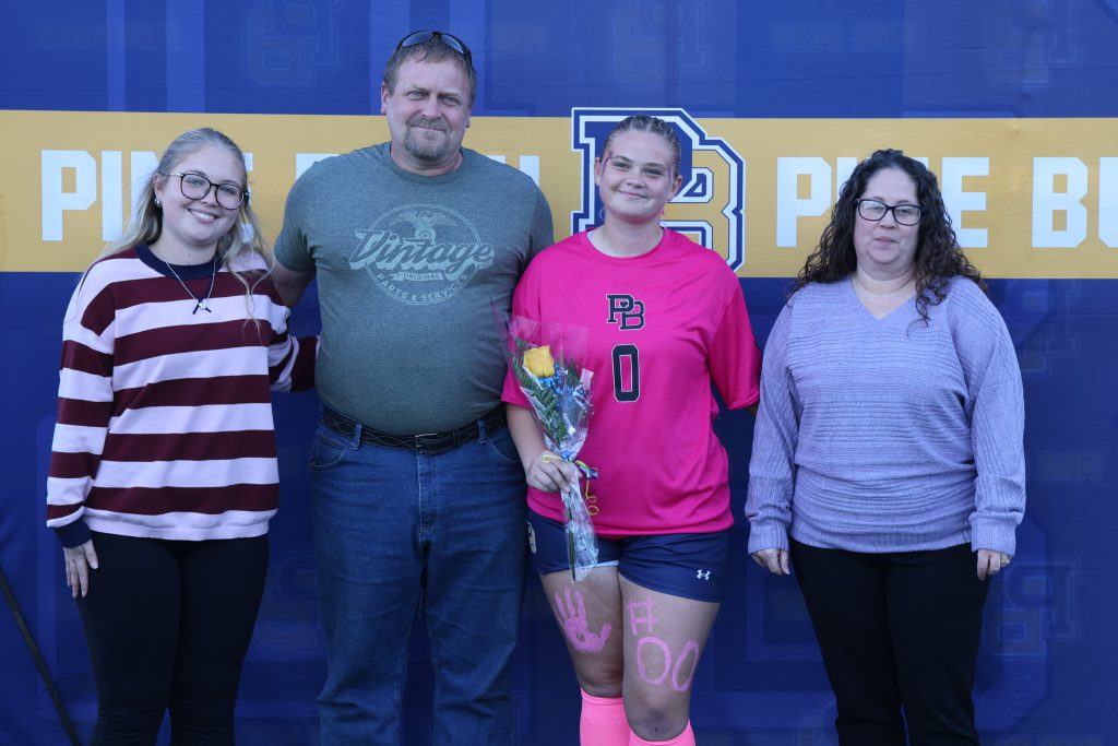 high school soccer player standing with their parents
