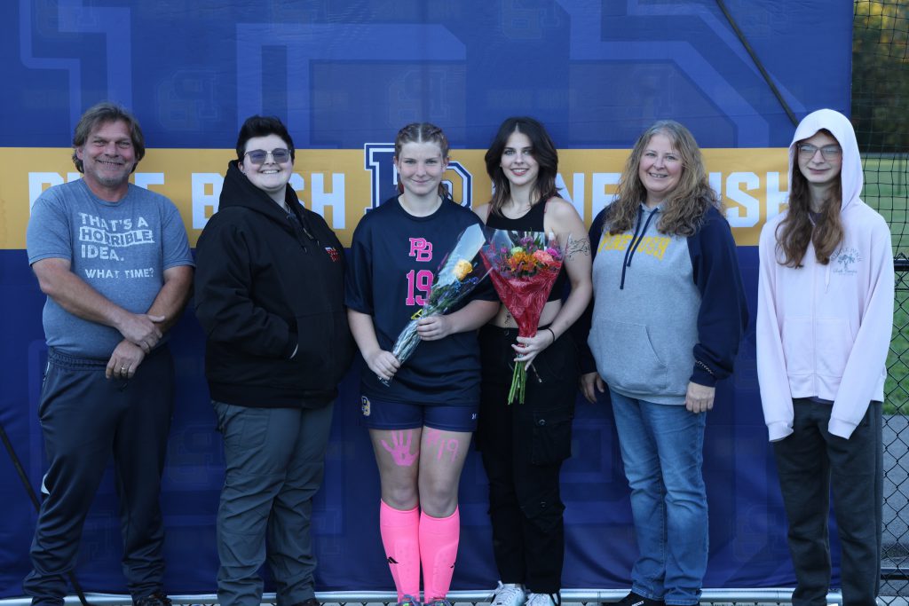high school soccer player standing with their parents