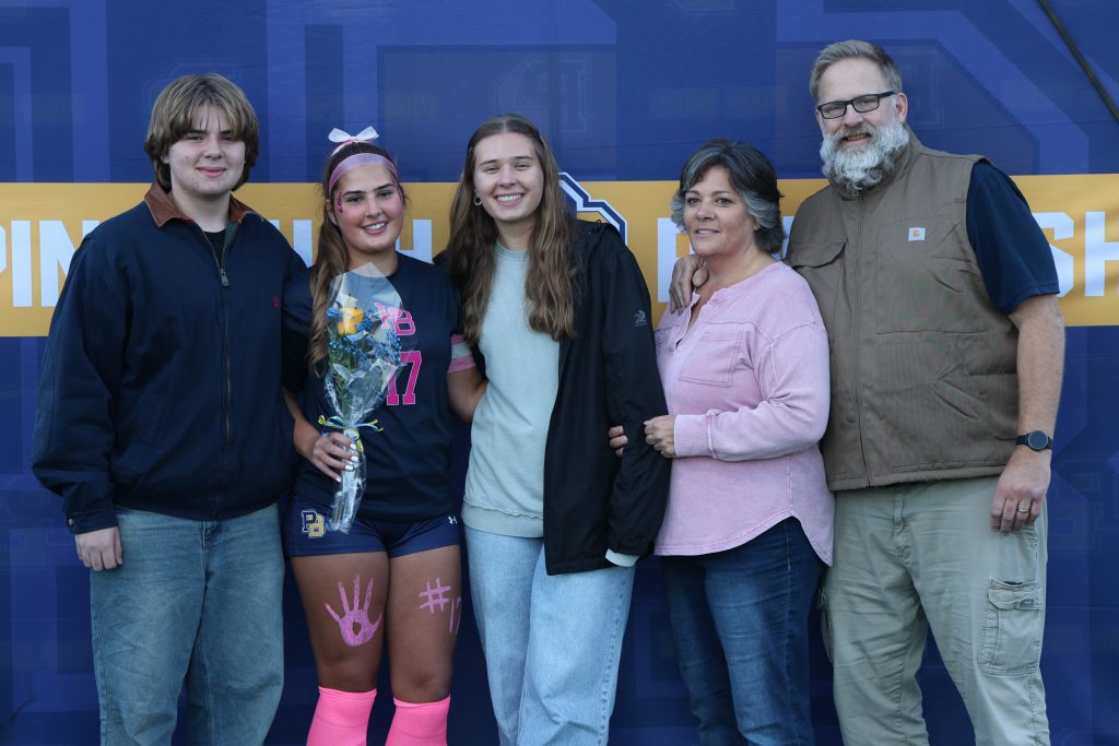 high school soccer player standing with their parents