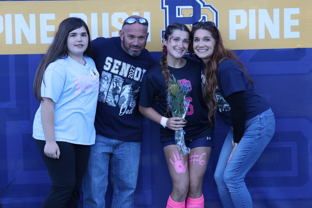 high school soccer player standing with their parents