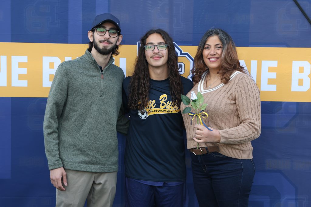 boys soccer player standing with his parents
