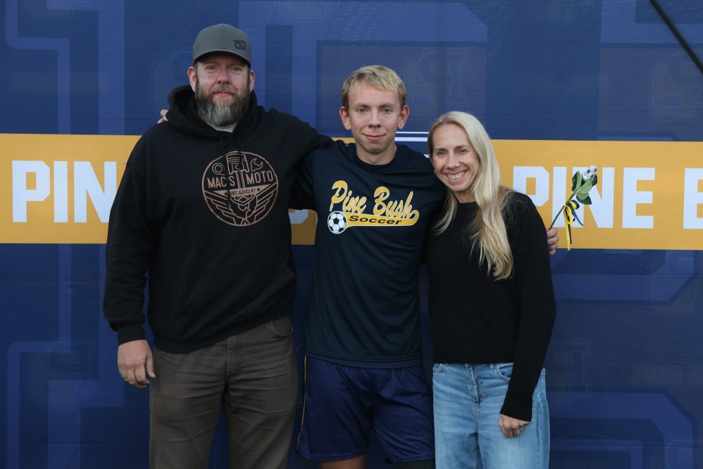 boys soccer player standing with his parents