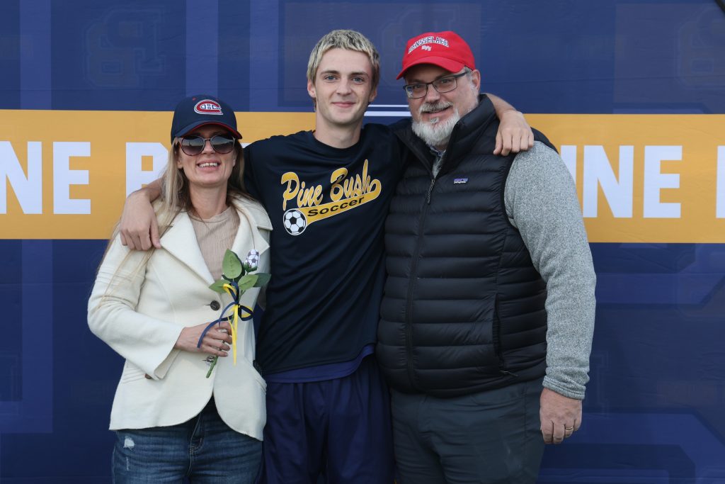 boys soccer player standing with his parents