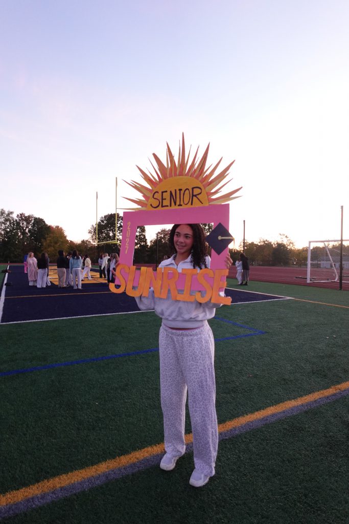 young girl holding up sign that says senior sunrise