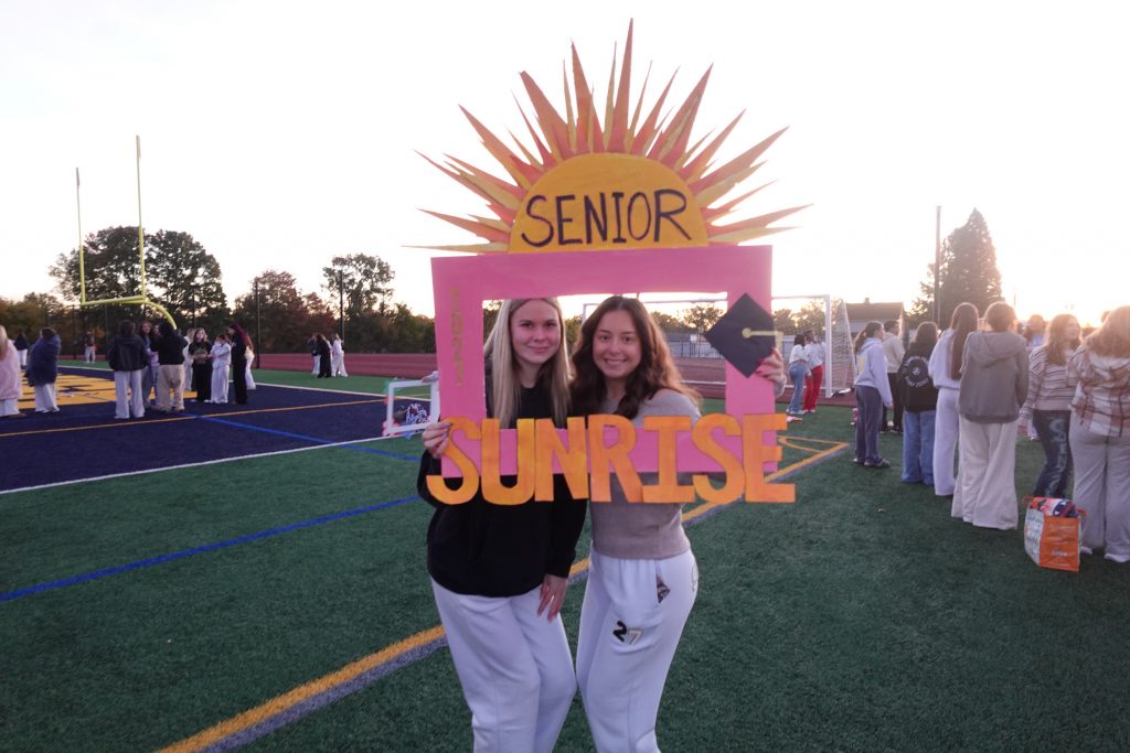 two girls holding up a sign that says senior sunrise