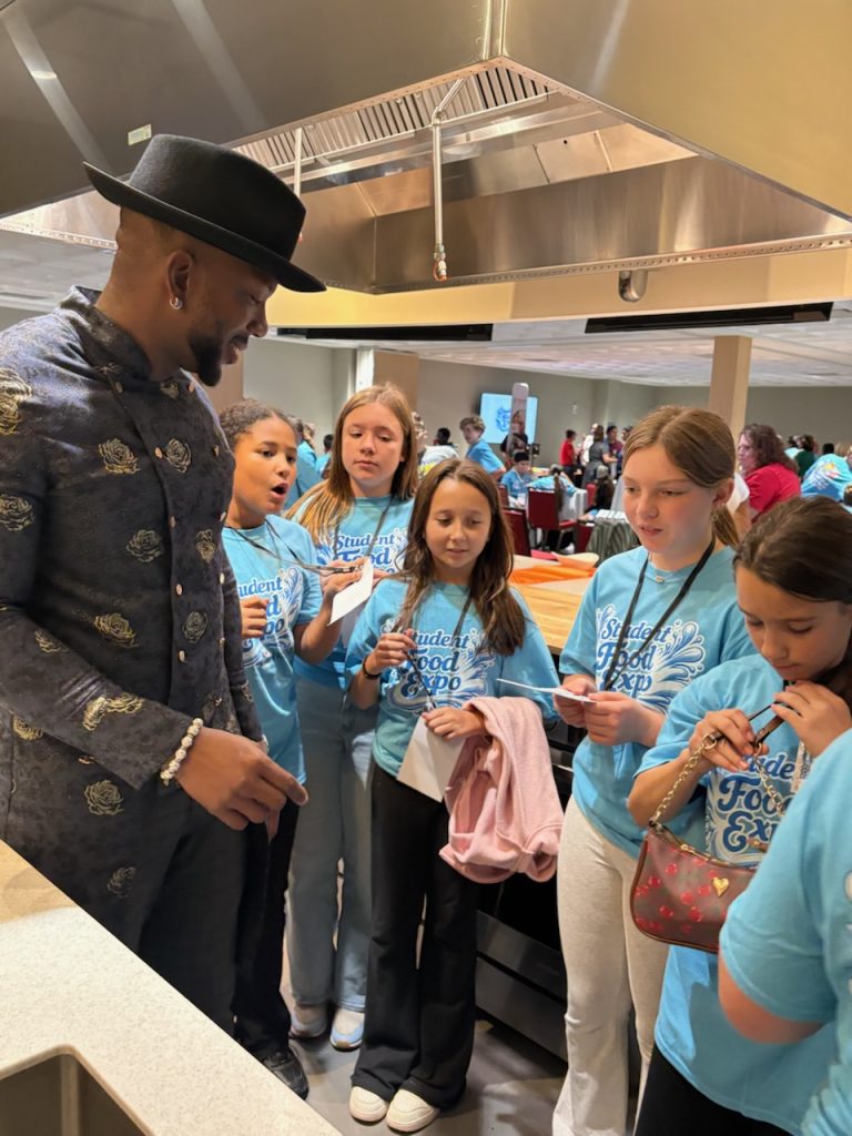 high school students talking to a chef in a kitchen