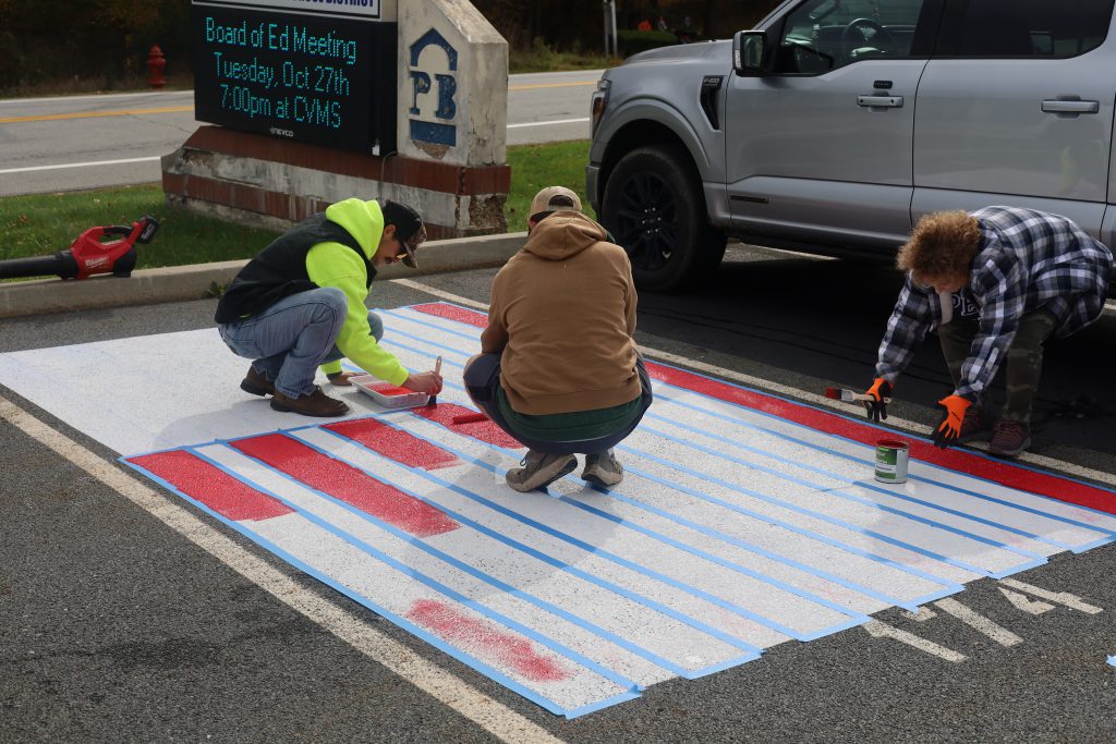 high school students painting on a parking spot