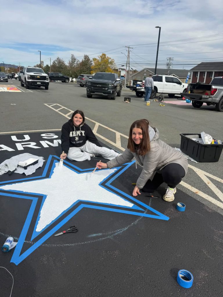 high school students painting a star on a parking space