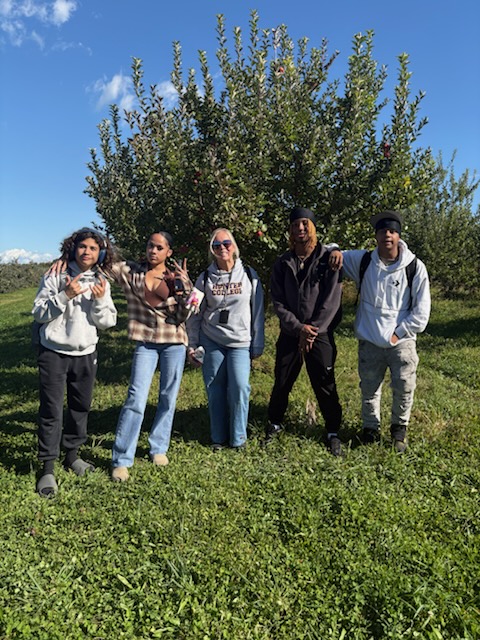 a group standing in an apple orchard