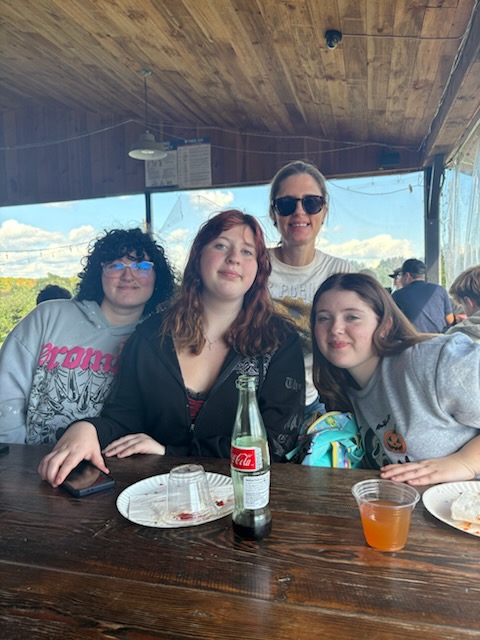 group of girls and their teacher sitting at a table outdoors