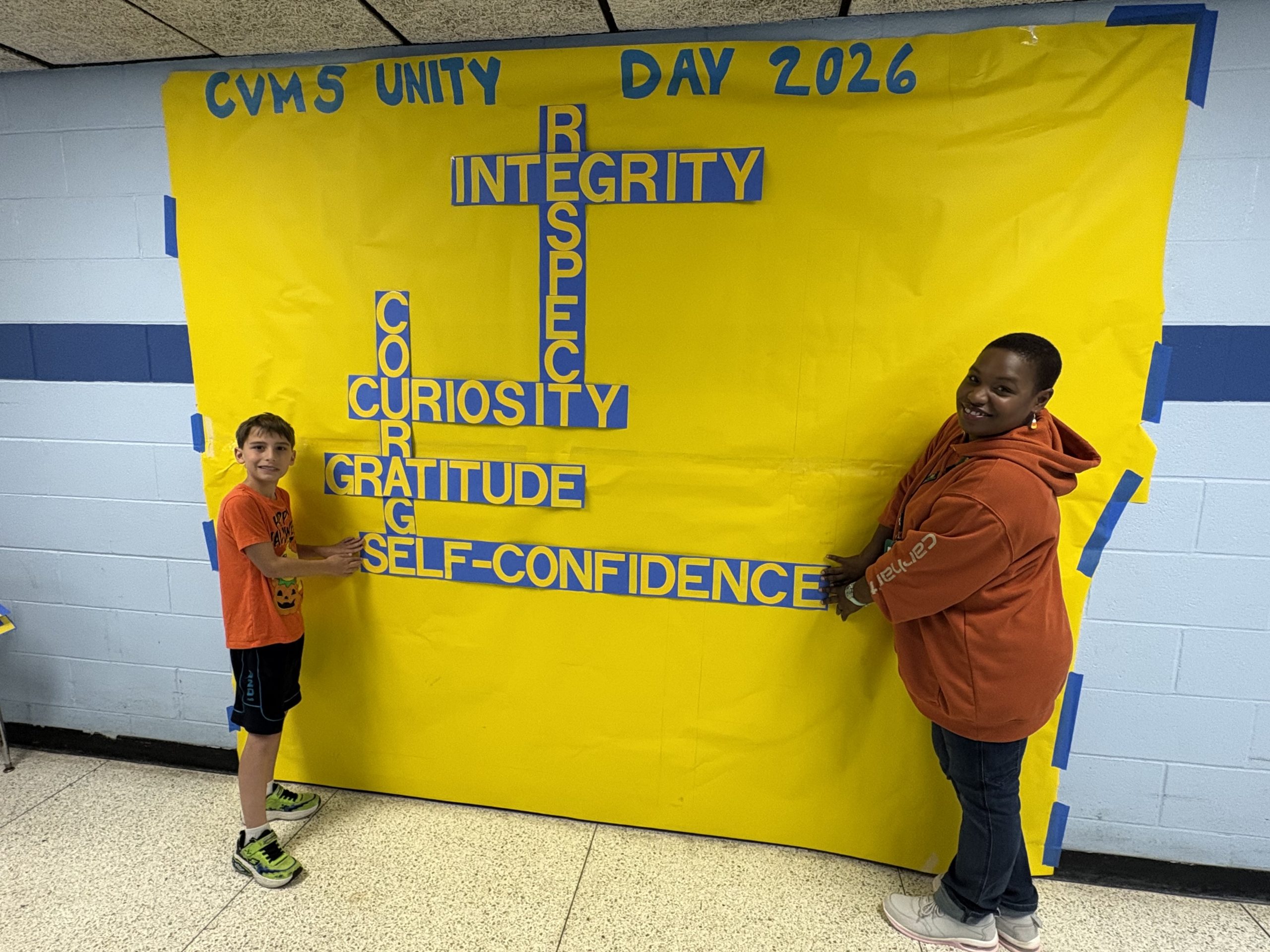 middle school students standing in front of a banner