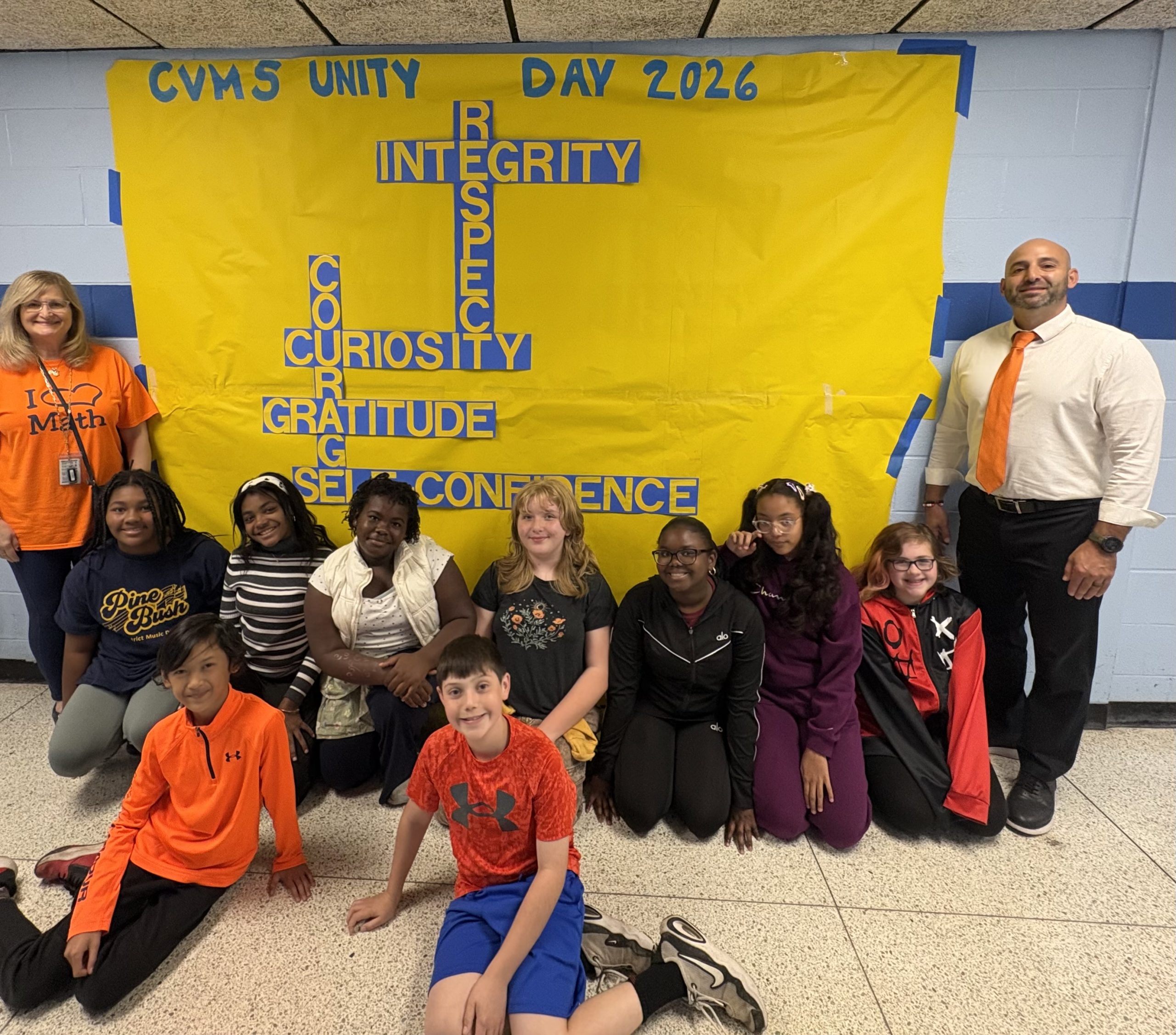 group of kids sitting on the floor with their teachers standing behind them